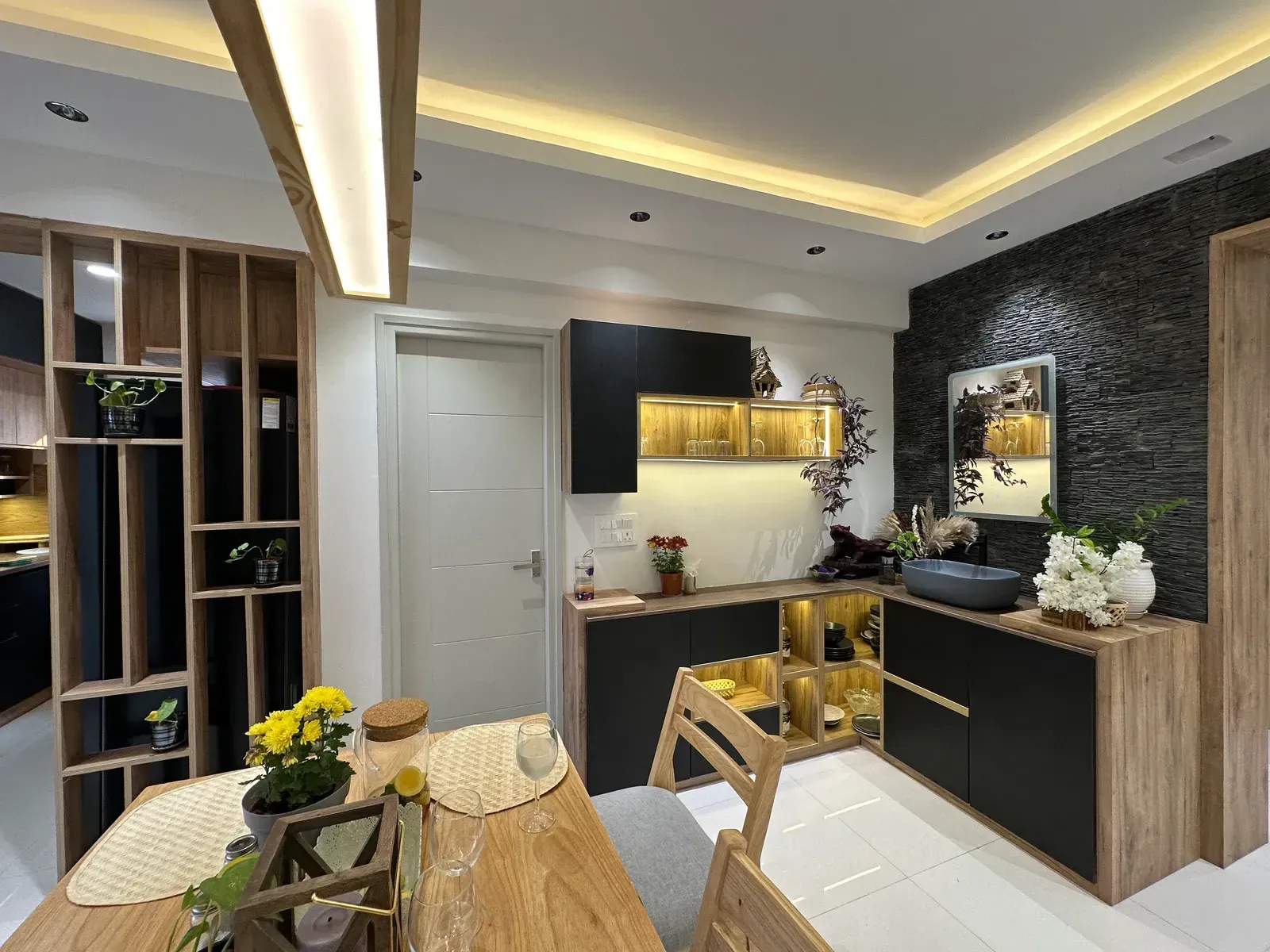 Dining area with oak shelving partition and black stone wall — The Aakar